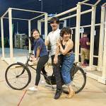 Victoria Chen, Dai Tabuchi, and Ami Okumura Jones all sitting on a bike and looking behind them.